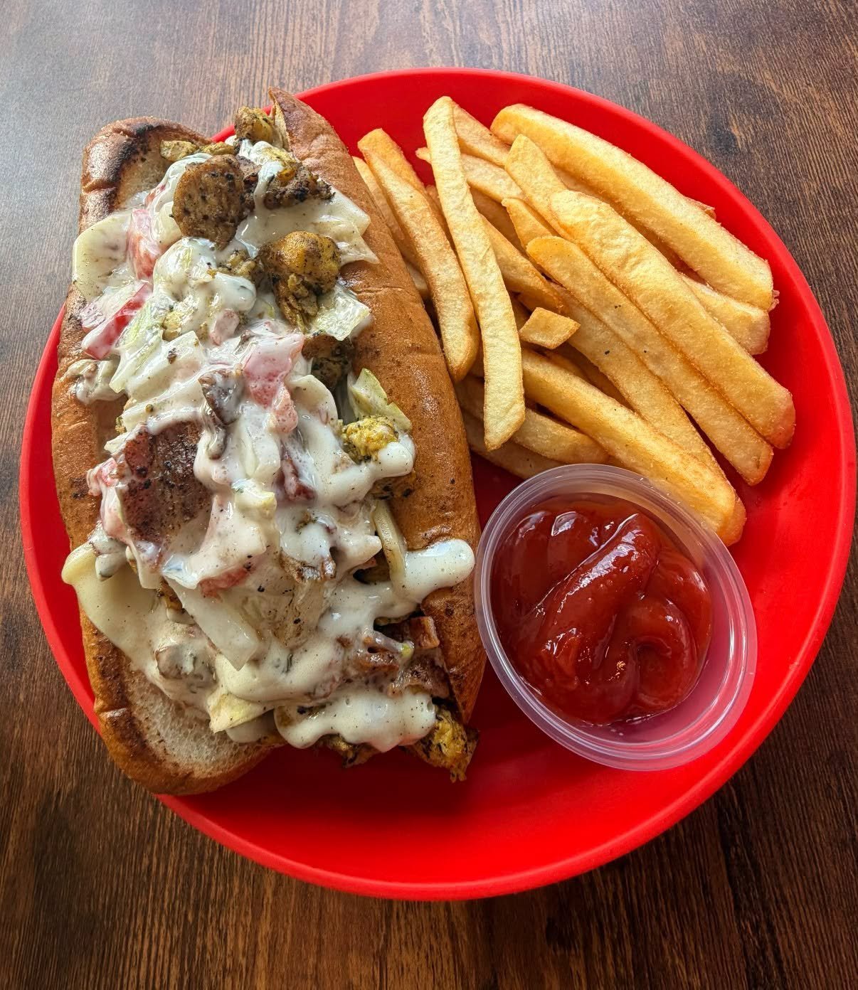 Loaded sub sandwich with creamy sauce and a side of fries