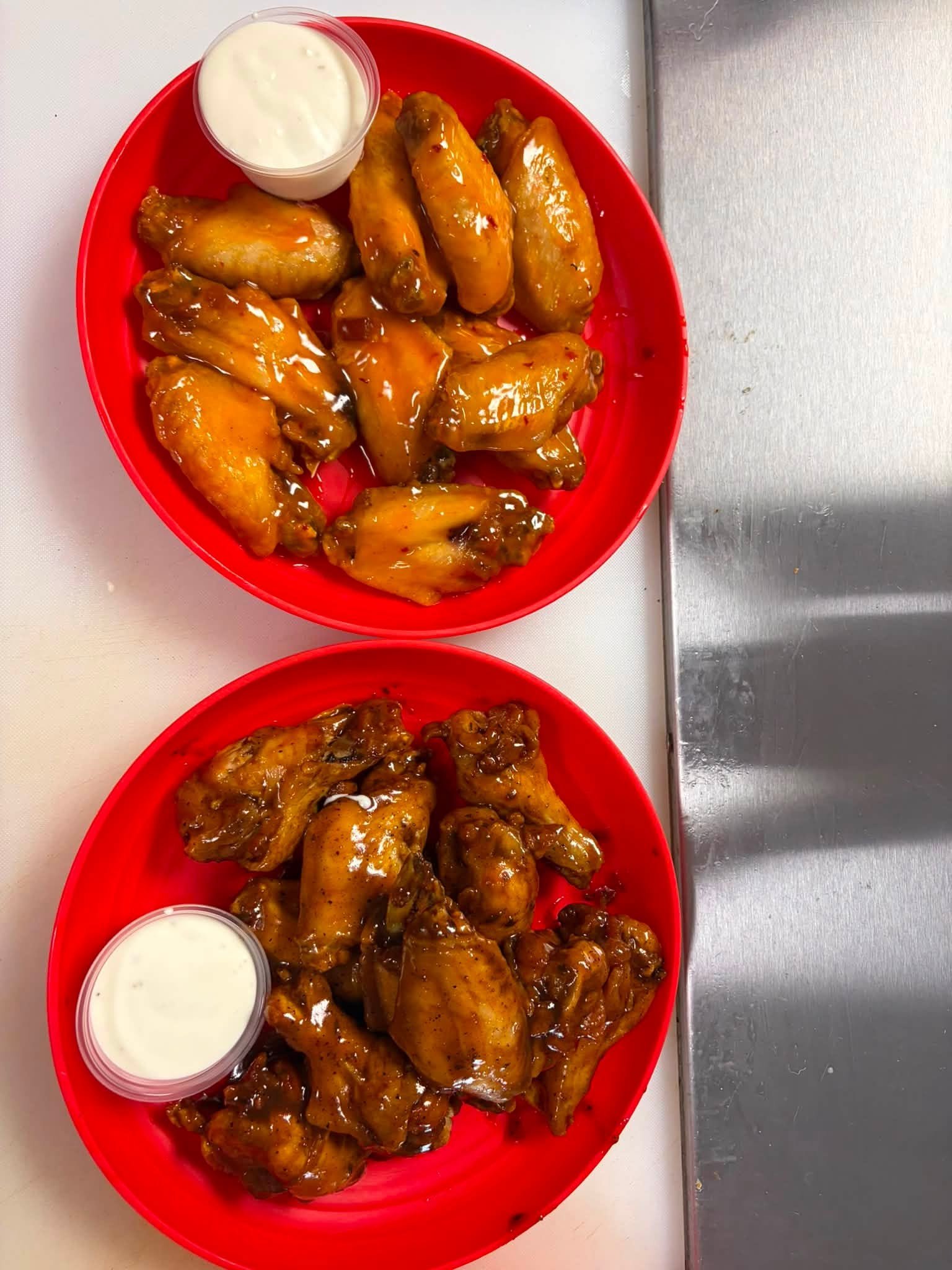 Two plates of saucy chicken wings with ranch
